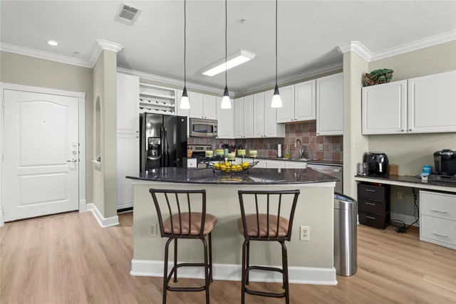 a kitchen with stainless steel appliances granite countertop a stove top oven a refrigerator a sink and a dining table with wooden floor