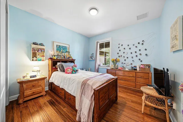 a bedroom with a bed next to a window with wooden floor