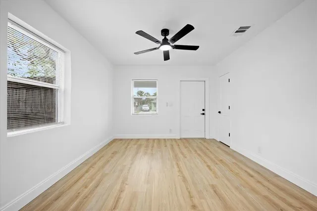 a view of empty room with wooden floor and fan