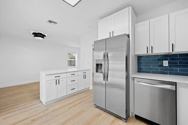 a kitchen with white cabinets and stainless steel appliances