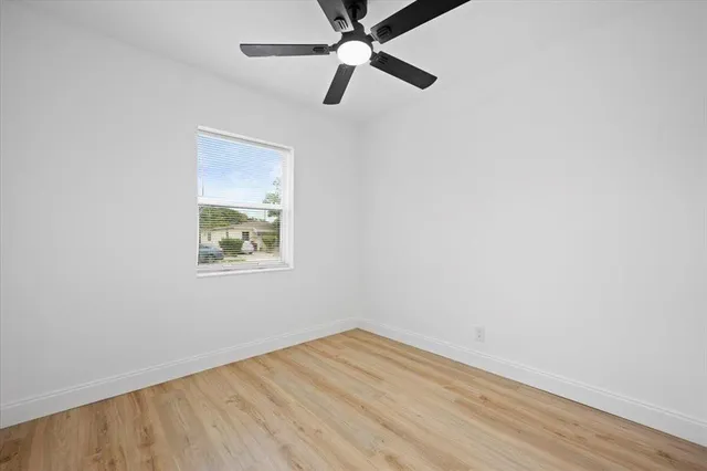 an empty room with a window and a ceiling fan