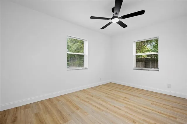 a view of empty room with wooden floor and fan