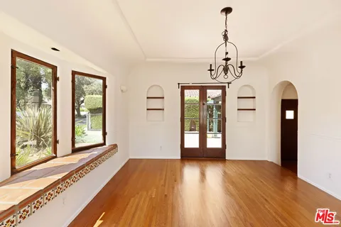 a view of a room with wooden floor chandelier and windows
