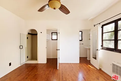 a view of empty room with wooden floor and fan