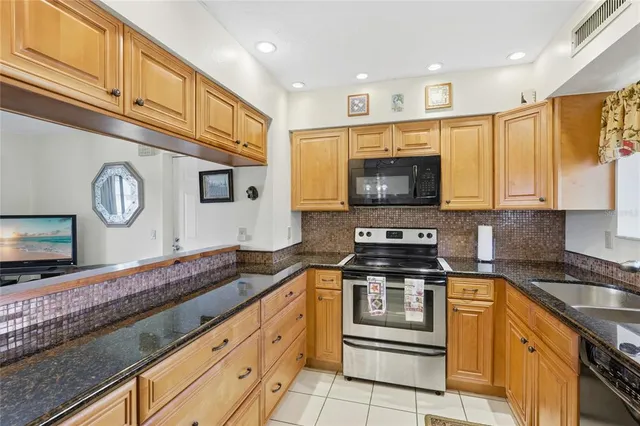 a kitchen with granite countertop a stove a sink and a microwave