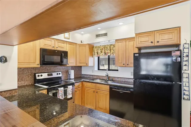 a kitchen with stainless steel appliances kitchen island granite countertop a refrigerator and a stove top oven