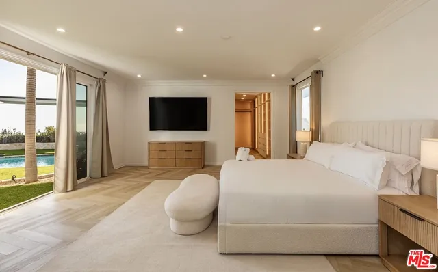 a bedroom with a bed and a flat tv screen on dresser