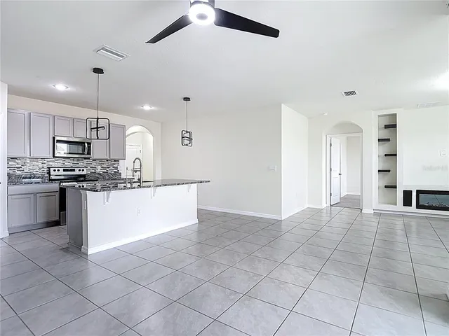 a view of an empty room with a stove top oven and kitchen view