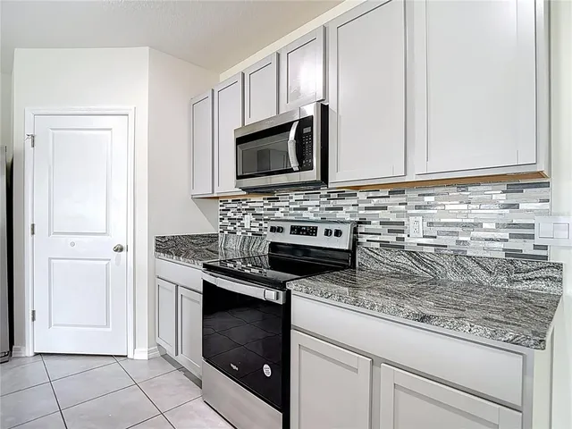 a kitchen with kitchen island granite countertop stainless steel appliances a stove a sink and a refrigerator