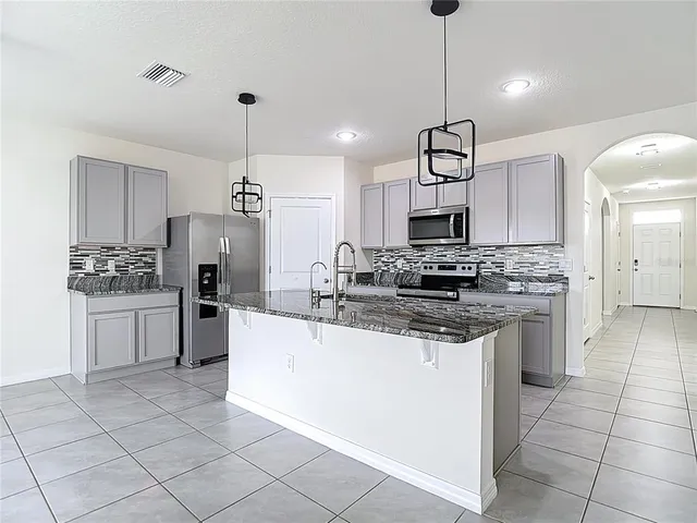 a kitchen with stainless steel appliances granite countertop a sink a refrigerator and window