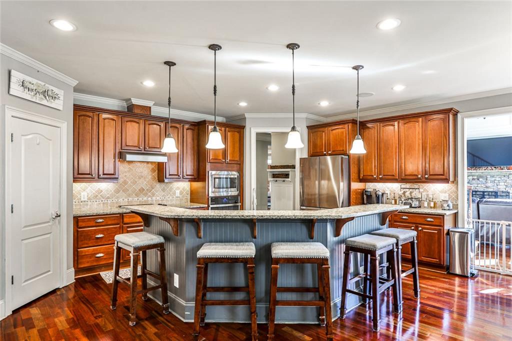 872 Pathview Court Dacula, GA 30019 - Photo 14 of 62 a kitchen with stainless steel appliances granite countertop a stove a refrigerator a kitchen island a dining table and chairs with wooden floor