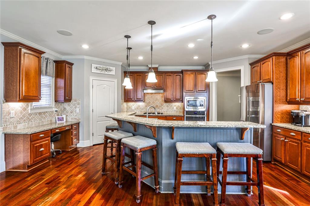 872 Pathview Court Dacula, GA 30019 - Photo 15 of 62 a kitchen with stainless steel appliances granite countertop a kitchen island hardwood floor sink stove dining table and chairs