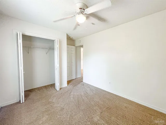 an empty room with closet and a ceiling fan