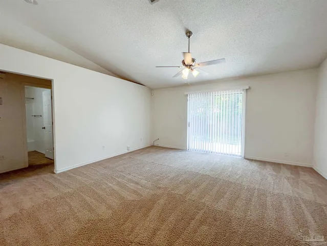 a view of an empty room with chandelier fan and windows