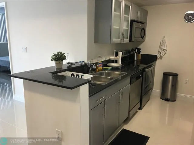 a kitchen with stainless steel appliances granite countertop a sink and a refrigerator