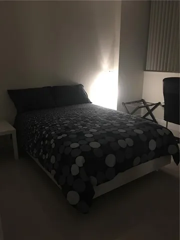 a bedroom with a bed next to a window with wooden floor