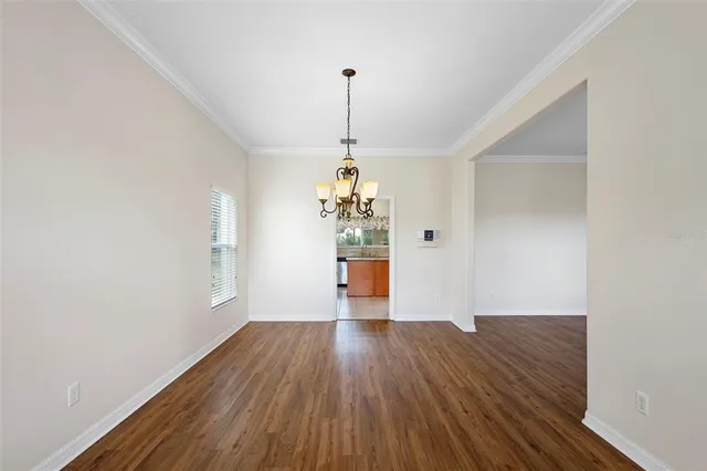 a big room with wooden floor a chandelier fan and windows