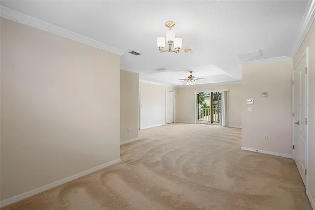 a view of an empty room with a chandelier fan