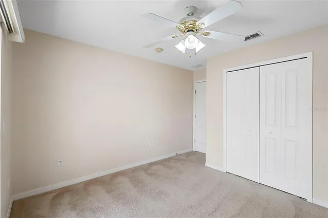 an empty room with a chandelier fan and windows