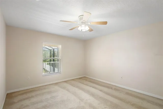 an empty room with a window and ceiling fan