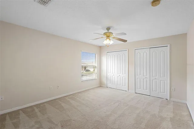 an empty room with windows and chandelier fan