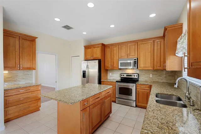 a kitchen with stainless steel appliances granite countertop a stove a sink and a refrigerator