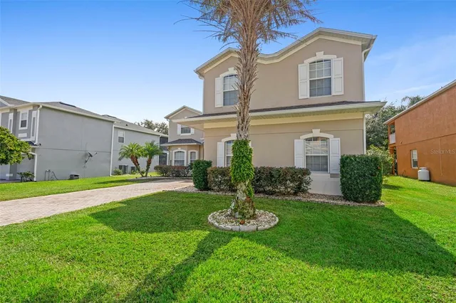 a front view of a house with a yard and potted plants