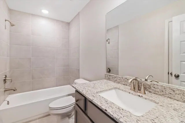 a bathroom with a granite countertop sink a toilet and bathtub