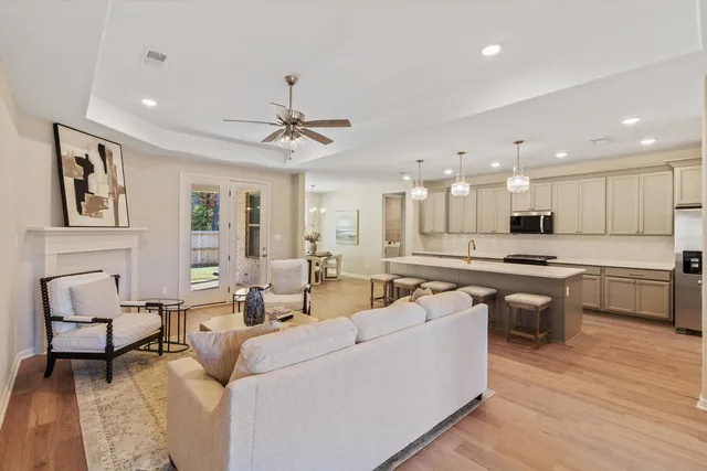 a living room with couches and kitchen view with wooden floor