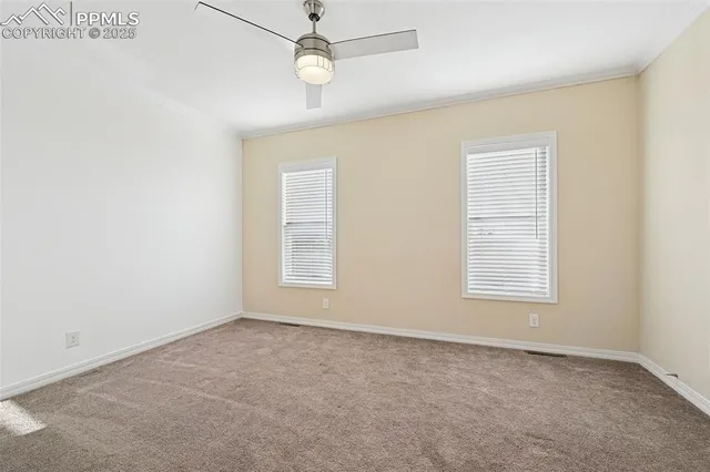 an empty room with windows and ceiling fan