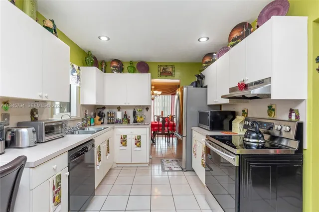 a kitchen with a stove a refrigerator sink dishwasher and cabinets with wooden floor