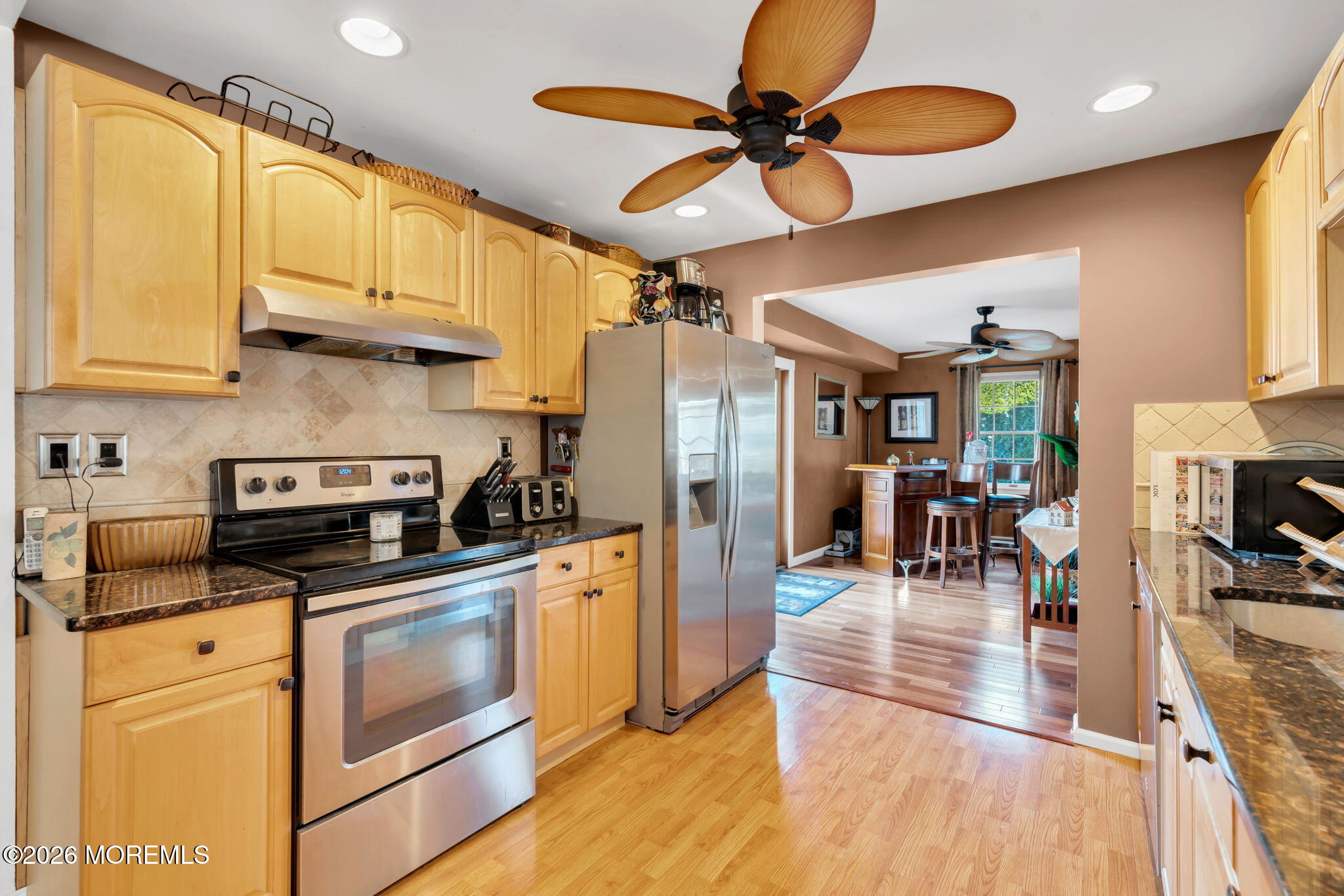 83 Seawood Drive Keyport, NJ 07735 - Photo 6 of 23 a kitchen with stainless steel appliances granite countertop a stove top oven a sink a dining table and chairs with wooden floor