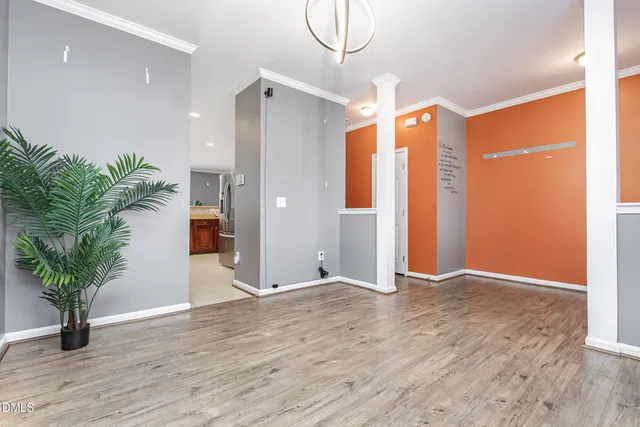 a view of an empty room with a window and wooden floor