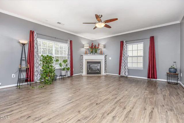 a view of an empty room with window and wooden floor