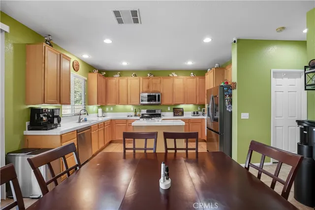 a kitchen with stainless steel appliances granite countertop table chairs stove and wooden floor