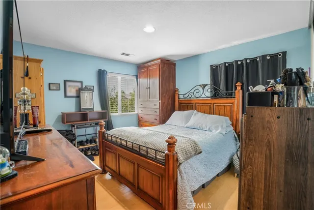 a bedroom with a bed and a flat tv screen on dresser