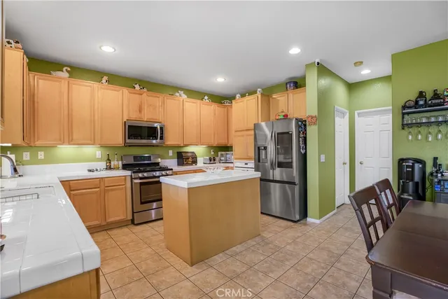 a kitchen with stainless steel appliances granite countertop a refrigerator stove top oven dining table and chairs