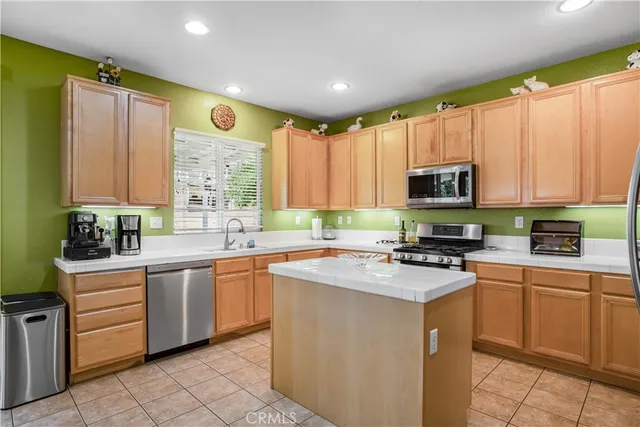 a kitchen with stainless steel appliances granite countertop white cabinets sink and a window