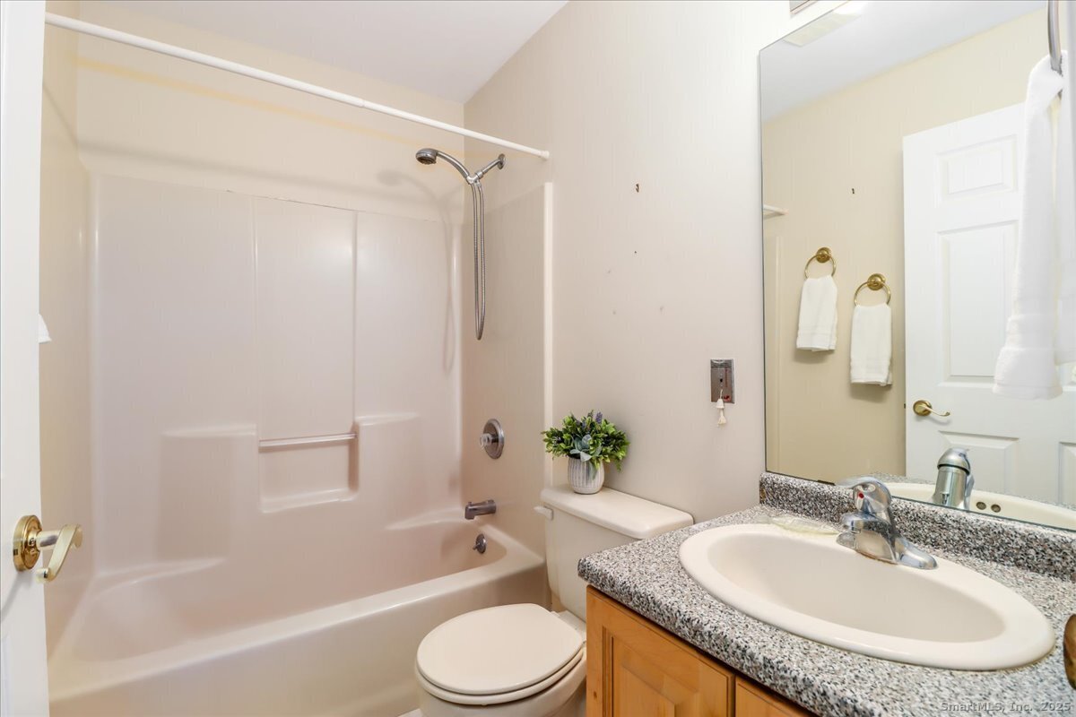 25 St George Place Newtown, CT 06482 - Photo 22 of 35 a bathroom with a granite countertop sink toilet a mirror a bathtub and shower
