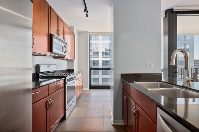 210 South Desplaines Street, Unit 2002 Chicago, IL 60661 - Photo 8 of 24 a kitchen with stainless steel appliances granite countertop a sink stove and cabinets