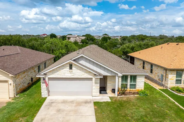 a view of a white house next to a yard with big trees