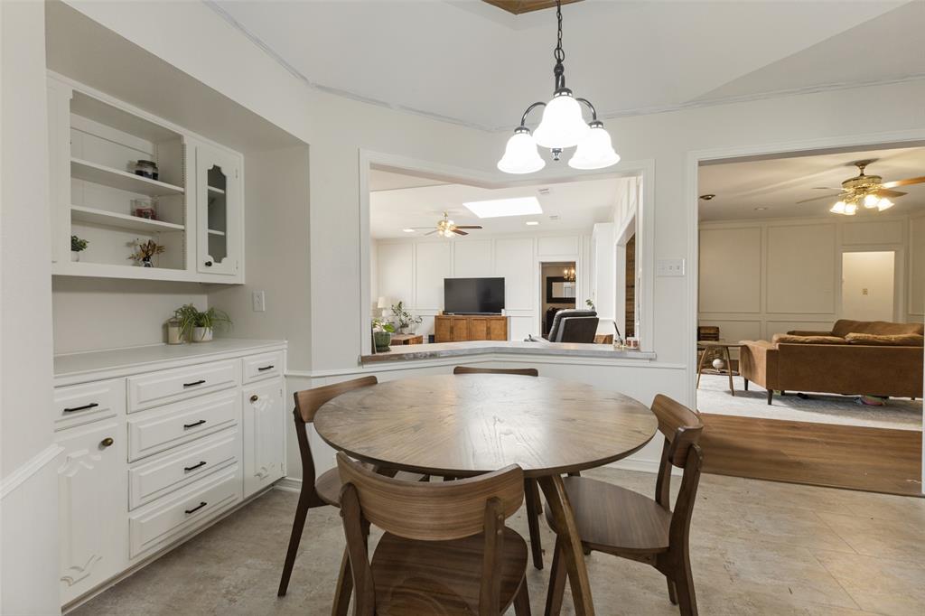 705 South Grove Road Richardson, TX 75081 - Photo 10 of 26 Dining area featuring a contemporary chandelier, built-in cabinetry, and a pass-through window to an additional living space