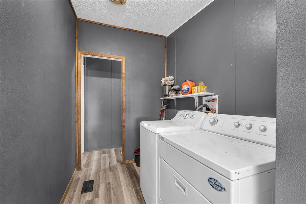 3615 Spring Valley Road Lorena, TX 76655 - Photo 27 of 33 Utility space featuring wood-finish flooring, dark gray wall paneling, and an exposed wood door frame
