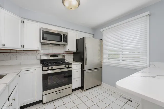 a kitchen with stainless steel appliances granite countertop a refrigerator and a stove top oven