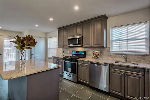 a kitchen with stainless steel appliances granite countertop a sink stove and microwave