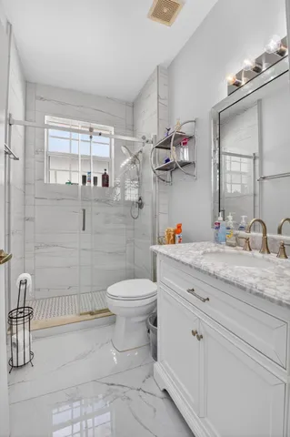 a bathroom with a granite countertop sink a toilet and a shower