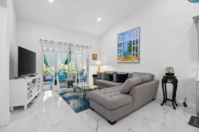 a living room with furniture a flat screen tv and a floor to ceiling window
