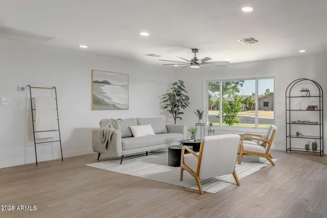a living room with furniture a large window and wooden floor