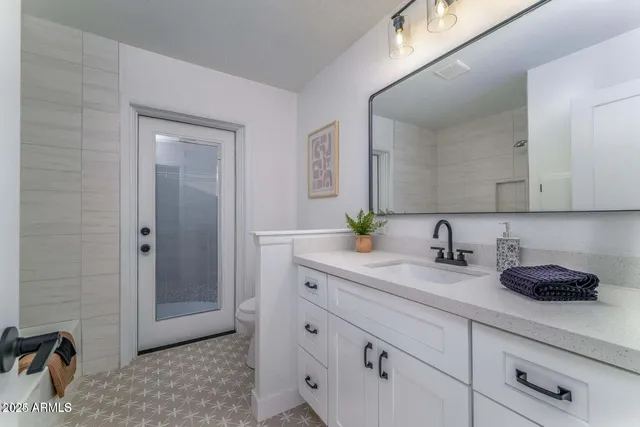 a bathroom with a granite countertop sink a toilet and mirror