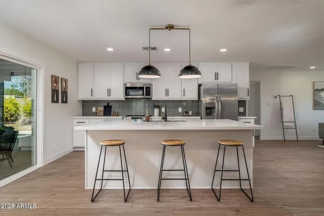 a kitchen with stainless steel appliances kitchen island granite countertop a table chairs sink and cabinets